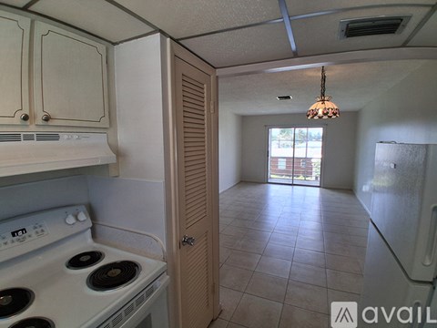 A kitchen with a stove top oven and a door leading to a hallway.