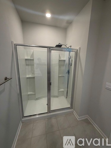 A glass shower stall with a glass door and a glass shelf.