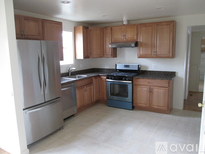 A kitchen with wooden cabinets and a stainless steel refrigerator.