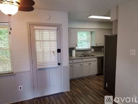 A kitchen with white cabinets and a brown door.