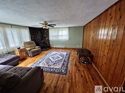 A living room with wooden walls and a rug on the floor.