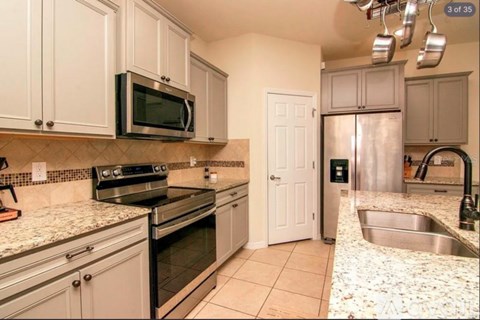 A kitchen with a black microwave above a stove and a stainless steel refrigerator.