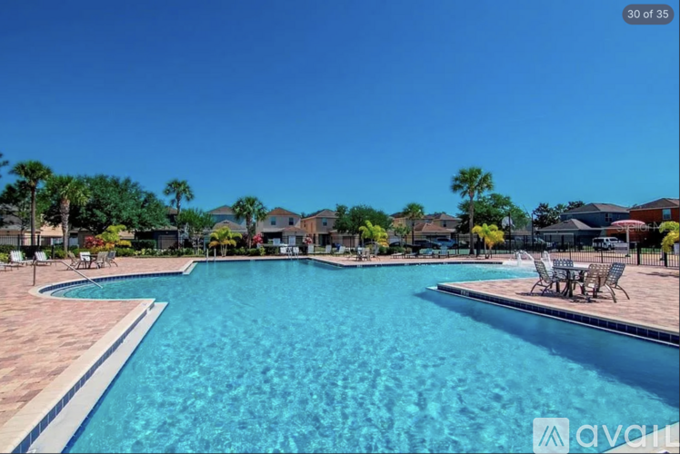 A large swimming pool surrounded by a patio and chairs.
