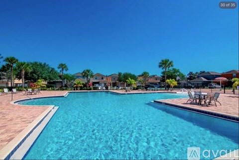 A large swimming pool surrounded by a patio and chairs.