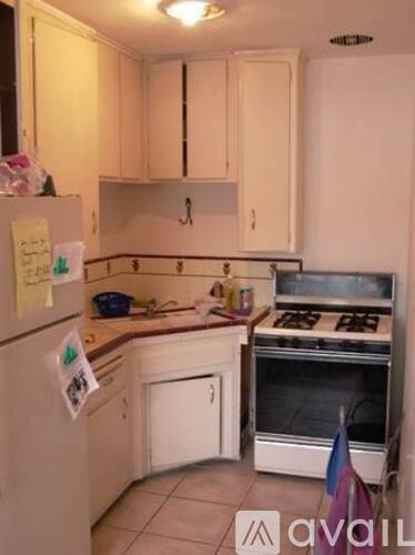A kitchen with a white refrigerator, white cabinets, and a white stove top oven.