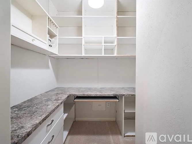 A kitchen with a marble countertop and white cabinets.
