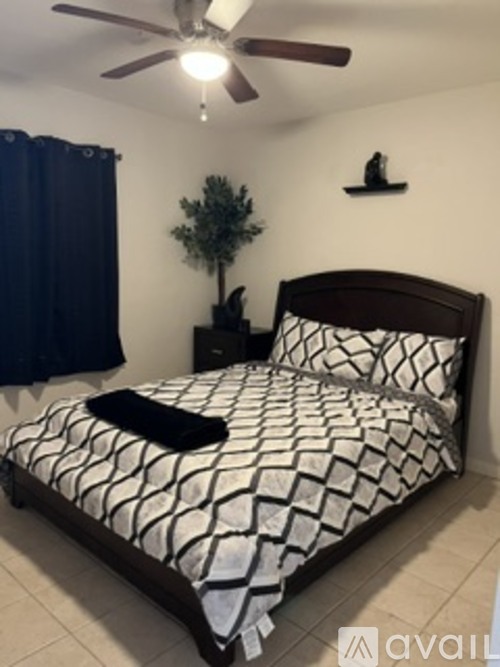 A bedroom with a bed, a ceiling fan, and a small plant on a nightstand.