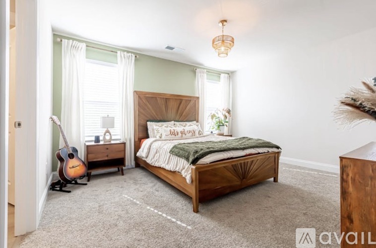 A bedroom with a bed, a guitar, and a window.