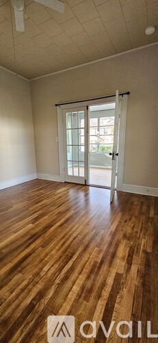A room with wooden flooring and a sliding glass door.