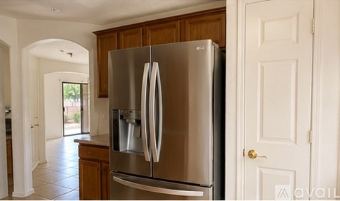 A stainless steel refrigerator in a kitchen with wooden cabinets.