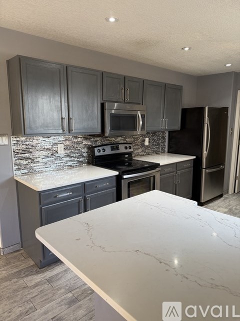 A kitchen with a marble countertop and dark grey cabinets.