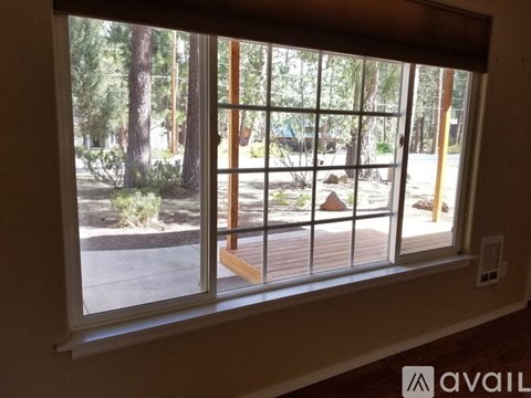 A window with a view of a wooden deck and trees outside.