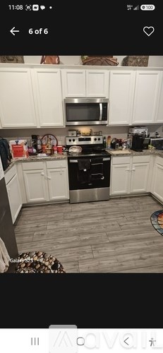A kitchen with white cabinets and a black stove top oven.