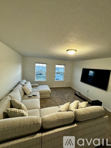 A living room with a large couch and a flat screen TV mounted on the wall.