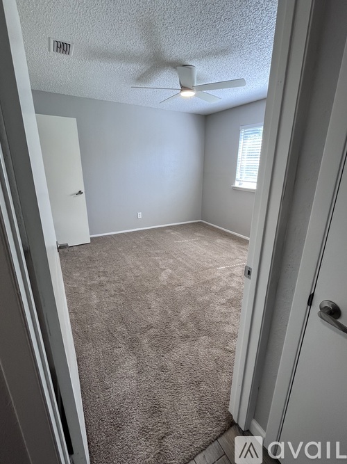 A room with a carpeted floor and a ceiling fan.