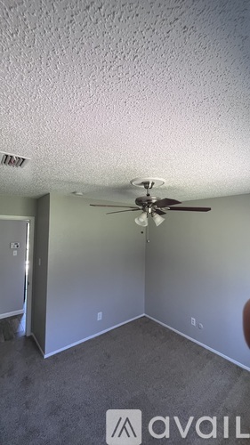 A room with a ceiling fan and carpeted floor.