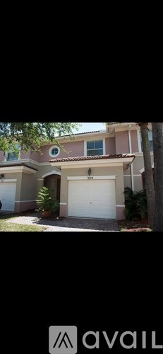 A house with a white garage door and a tree in front.