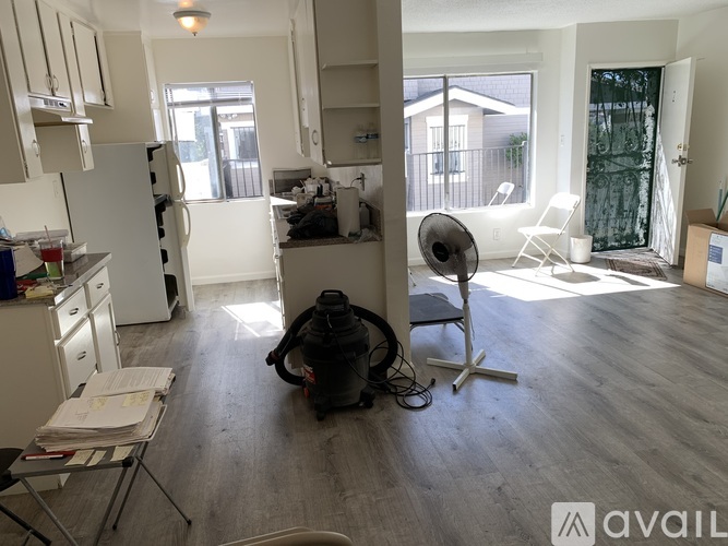 A man is sitting on the floor in a kitchen with a camera on a tripod.