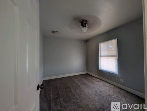 A room with a carpeted floor and a window with blinds.