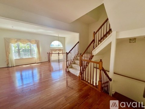 A spacious room with wooden floors and a staircase.