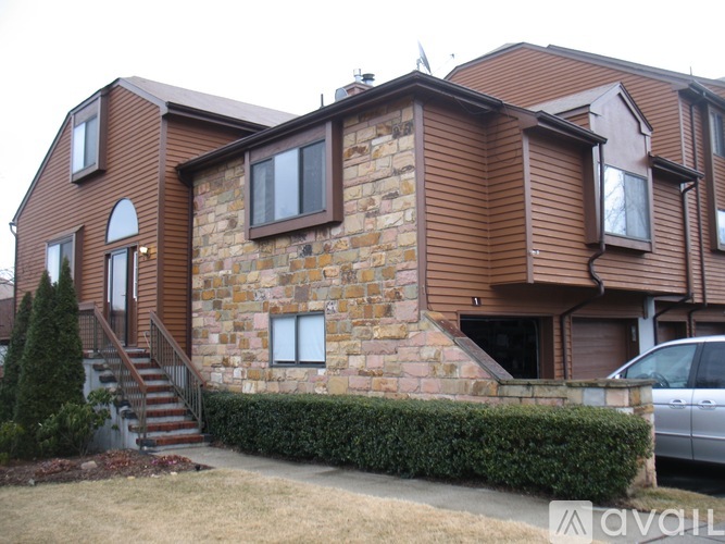 A brown house with a stone wall and a car parked in front.