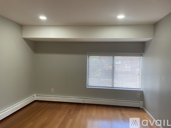 A room with wooden flooring and a window with blinds.