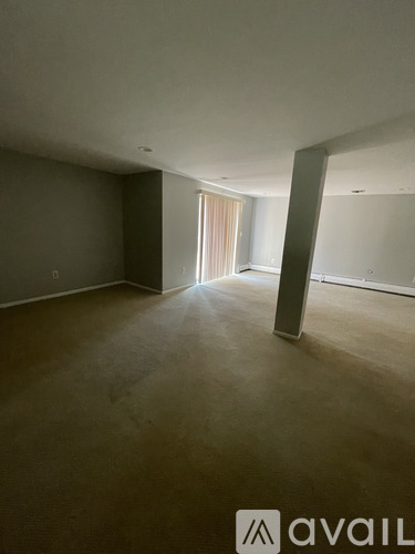 A spacious room with a large window and a door leading to another room.