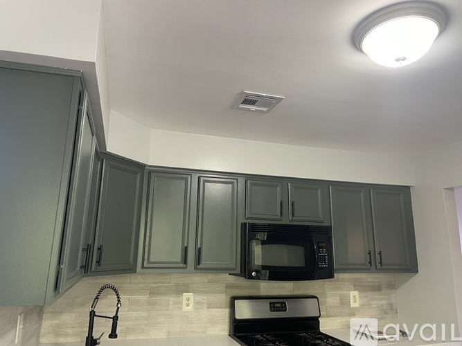 A kitchen with a black microwave oven and a black stove top oven.