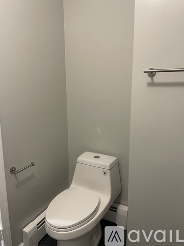 A white toilet in a small bathroom with a towel bar on the wall.