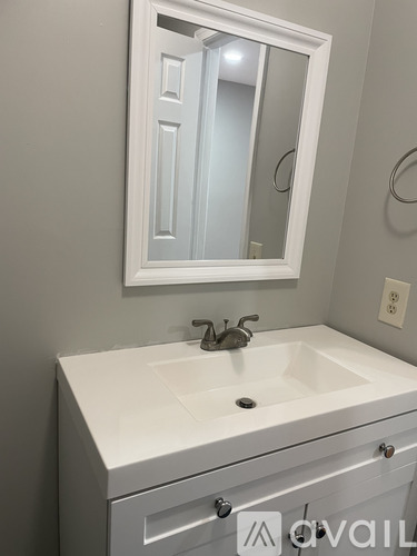 A white sink with a silver faucet and a mirror above it.