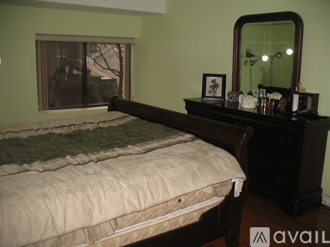 A bedroom with a bed, dresser, and mirror.