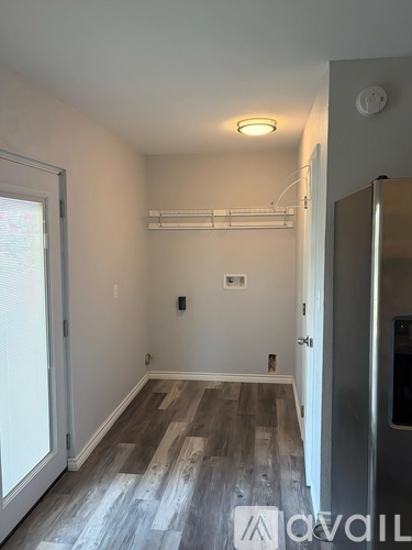 A room with a wooden floor and a white ceiling with a smoke detector.