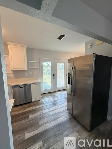 A kitchen with a refrigerator, dishwasher, and a sink.