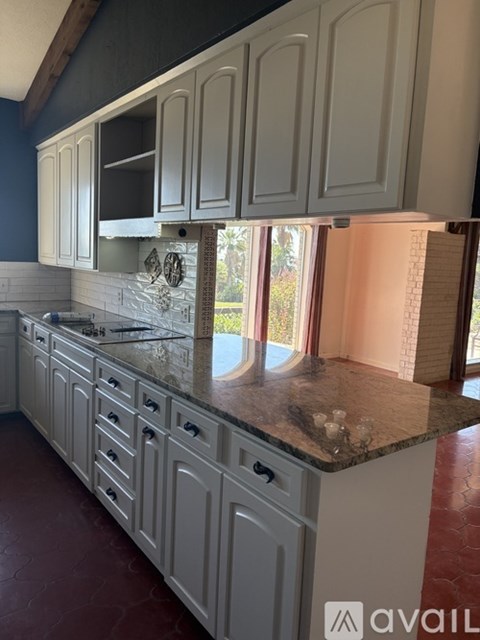 A kitchen with white cabinets and a marble countertop.