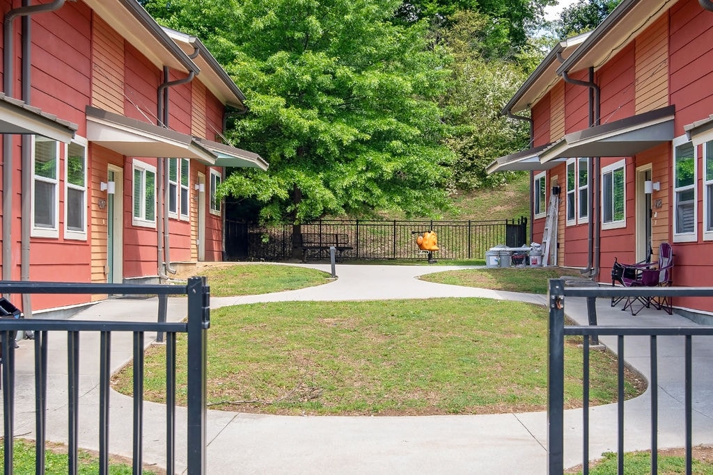 A red building with a black fence and a green lawn in front.