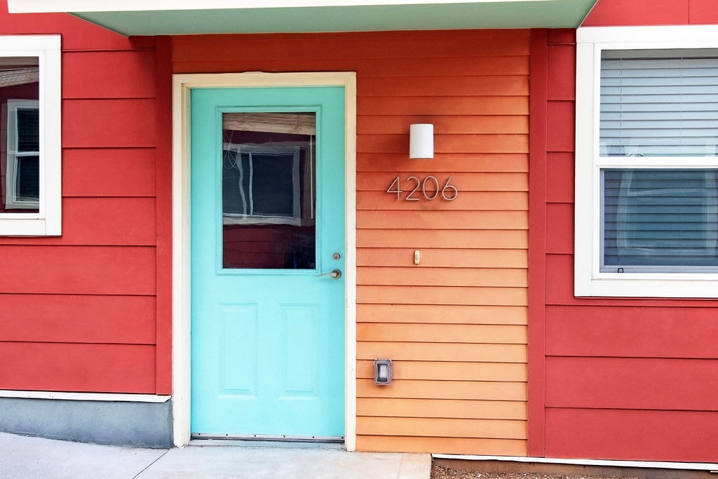 A red house with a blue door and a number 4206 on the wall.