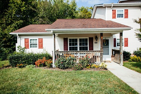 A white house with red shutters and a brown roof.