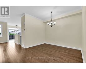 A spacious room with wooden flooring and a chandelier hanging from the ceiling.