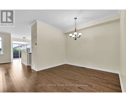 A spacious room with wooden flooring and a chandelier hanging from the ceiling.