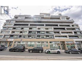 A modern multi-story building with cars parked in front.