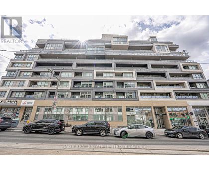 A modern multi-story building with cars parked in front.