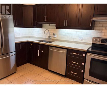 A kitchen with dark brown cabinets and a stainless steel refrigerator.