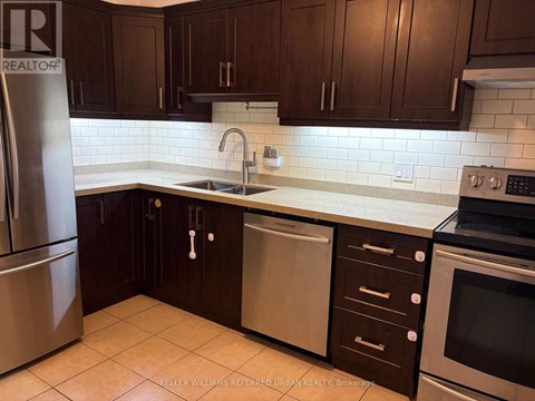 A kitchen with dark brown cabinets and a stainless steel refrigerator.