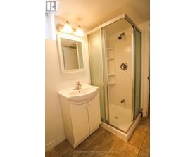 A white sink and cabinet in a bathroom with a glass shower door.
