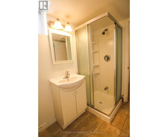 A white sink and cabinet in a bathroom with a glass shower door.