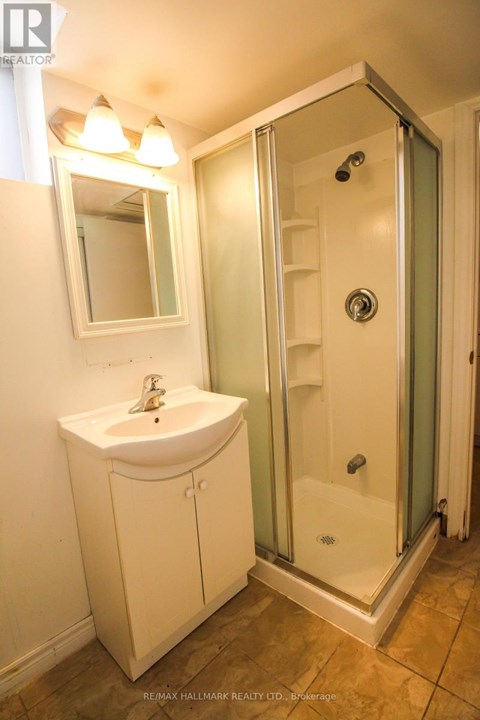 A white sink and cabinet in a bathroom with a glass shower door.