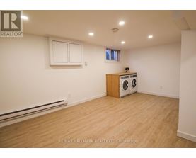 A room with a wood floor, a window, and a wall-mounted heater.