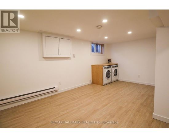 A room with a wood floor, a window, and a wall-mounted heater.