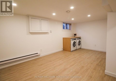 A room with a wood floor, a window, and a wall-mounted heater.