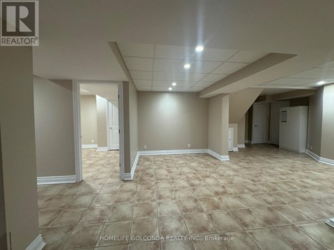 A spacious room with beige carpeting and white walls, with a logo for REALTOR® in the top left corner.